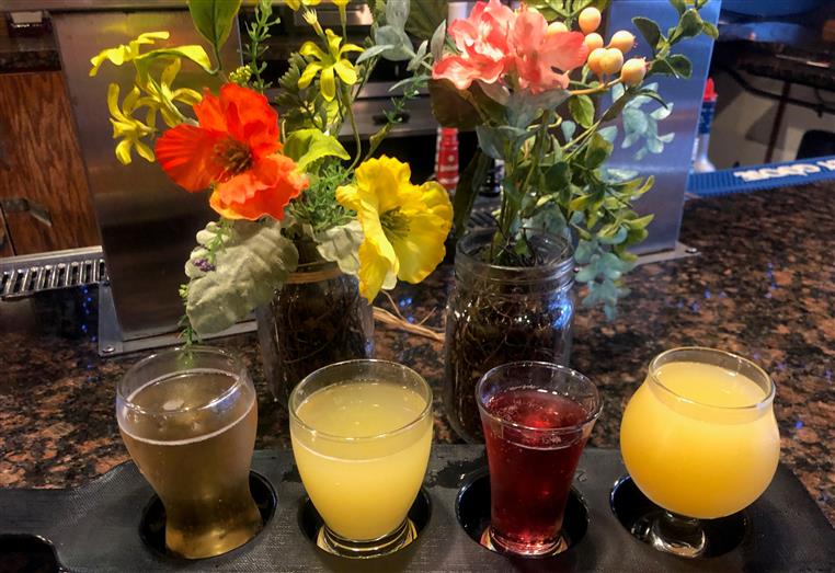 flight of assorted drinks with flowers behind it.